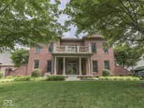 Stately brick home featuring a manicured lawn, mature trees, and a charming front porch with columns at 20 Forrests Edge Ct, Indianapolis, IN 46227