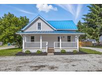 Charming home with a blue metal roof and welcoming front porch, set against a bright blue sky at 300 N Church St, Arcadia, IN 46030