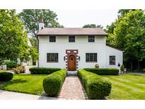 Charming two-story home featuring a brick-accented entryway and beautifully landscaped front yard with manicured hedges at 5805 Forest Ln, Indianapolis, IN 46220