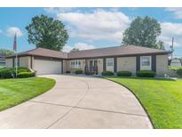 Charming brick ranch home with lush lawn, curved driveway, and attached two car garage at 8209 Burn Ct, Indianapolis, IN 46217