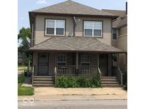 Two-story home with front porch featuring brick accents, gray siding and roofing, and traditional windows at 1421 S Meridian St, Indianapolis, IN 46225