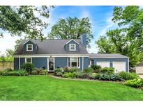 Charming blue home featuring a well-manicured lawn and vibrant flower beds at 3940 E 57Th St, Indianapolis, IN 46220