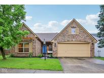 Charming brick home featuring a two-car garage, well-manicured lawn, and a bright blue front door at 4933 Common Vista Way, Indianapolis, IN 46220