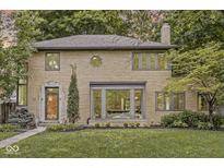 Charming brick home boasts mature trees, a landscaped yard, and unique architectural details at 518 Buckingham Dr, Indianapolis, IN 46208