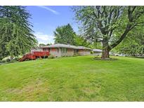 Expansive backyard with a lush lawn, mature trees, red patio and a well-maintained exterior at 7061 Maryann Ct, Indianapolis, IN 46227