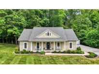 Charming home with a welcoming front porch, manicured lawn, and lush greenery at 7074 E Pine Needle Ln, Morgantown, IN 46160