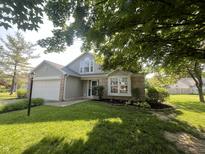 Charming home featuring a well-manicured lawn, brick accents, and an attached two-car garage at 7657 Winding Creek Dr, Indianapolis, IN 46236