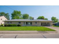 Charming single-story home featuring stone facade, well-manicured lawn, mature trees and attached carport at 1460 W Mckay Rd, Shelbyville, IN 46176