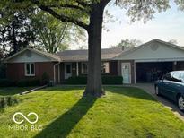 Charming brick ranch-style home with attached garage and mature shade tree in the front yard at 1637 Orchard Ln, Anderson, IN 46011