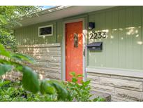 Close-up of the green house exterior featuring a red door and well-kept front yard at 2233 Washington St, Columbus, IN 47201