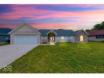 Charming single-story home featuring a brick and stone exterior with a well-manicured lawn and attached garage at 32 Downing Dr, Trafalgar, IN 46181