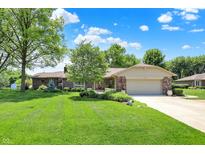 Ranch-style brick home with well-manicured lawn, mature trees, and attached two car garage at 5215 Limestone Ct, Indianapolis, IN 46237