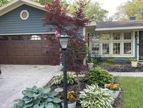 Charming home featuring mature landscaping, a brown garage door, and blue siding at 526 Emerson Rd, Carmel, IN 46032