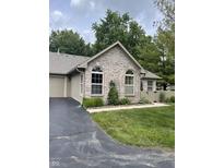 Charming home featuring a manicured lawn, arched windows, and a brick facade with beautiful landscaping at 7536 Briarstone Dr, Indianapolis, IN 46227