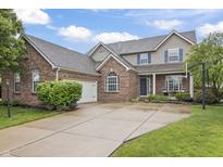 Charming two-story brick home with an attached garage and well-manicured lawn boasts inviting curb appeal at 8663 N Commonview Dr, McCordsville, IN 46055