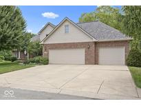 Charming home with a two-car garage, brick facade, and mature trees under a sunny sky at 9175 Lakewind Dr, Indianapolis, IN 46256