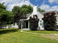Charming single-story home with a painted white brick chimney, mature trees, and lush lawn at 1141 N Shadeland Ave, Indianapolis, IN 46219