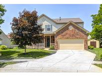 Charming two-story home boasts a brick-and-vinyl facade, well-manicured lawn, and an attached two-car garage at 13068 Lamarque Pl, Fishers, IN 46038