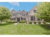 Charming two-story brick home featuring lush landscaping, a manicured lawn, and a welcoming front facade at 15201 Slateford Rd, Noblesville, IN 46062