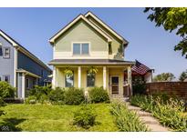 Charming two-story home featuring a covered front porch, lush landscaping, and an American flag at 2020 N Park Ave, Indianapolis, IN 46202