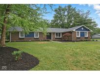 Charming brick home with blue accents, manicured landscaping, and a lush green lawn at 4645 Quail Run Dr, New Palestine, IN 46163