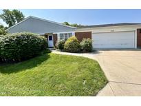 A well-maintained home with a green lawn, bushes, brick facade, and a two-car garage at 5491 Vin Rose Ln, Lawrence, IN 46226