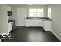 The bright kitchen features white cabinets, dark countertops, and stainless steel appliances at 620 S 2Nd St, Noblesville, IN 46060