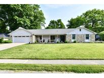 Charming single story home featuring stone accents, well-manicured lawn, and attached two car garage at 7242 Highburry Dr, Indianapolis, IN 46256