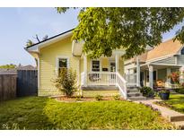 Charming yellow home with a welcoming front porch, green lawn, and lovely landscaping at 743 Sanders St, Indianapolis, IN 46203
