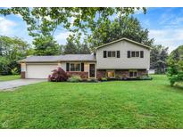 Charming split-level home with a well-maintained lawn and mature trees creating a welcoming curb appeal at 7504 Troon Ct, Indianapolis, IN 46237