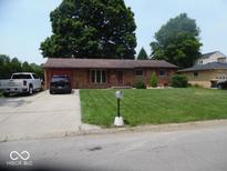 Charming single-story brick home featuring well-maintained lawn and mature trees at 213 S Coventry Dr, Anderson, IN 46012