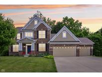 Charming two-story brick home boasting a three-car garage, well-manicured lawn and inviting curb appeal at 5441 Ellsworth Dr, Plainfield, IN 46168