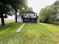 Two-story home with a brick and white exterior, front balcony, and a spacious lawn at 1445 S 750 W, Shelbyville, IN 46176