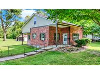 Charming brick home featuring a covered porch and landscaped front yard in a lush setting at 2601 Davis Rd, Indianapolis, IN 46239