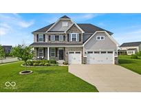 Charming two-story home featuring stone accents, gray siding, a manicured lawn, and a three-car garage at 4416 Eaglecrest Pl, Zionsville, IN 46077