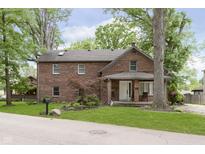 Charming two-story brick home with a cozy front porch and mature trees, offering classic curb appeal at 5110 S State Ave, Indianapolis, IN 46227