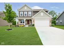 Inviting two-story home with landscaped lawn and a charming covered front porch and white two car garage at 5335 Rum Cherry Way, Indianapolis, IN 46237