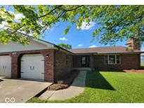 Charming brick home featuring an attached two-car garage and a well-manicured lawn at 724 Iroquois St, Anderson, IN 46012