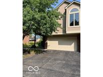 Beige two-car garage with beige siding and a large tree in front at 7707 River Rd # 10, Indianapolis, IN 46240