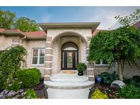 Elegant front entrance featuring arched doorway, brick accents, and landscaped garden at 8703 Gordonshire Dr, Indianapolis, IN 46278
