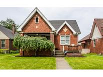 Charming brick home with a well-manicured lawn and a beautiful weeping willow tree at 948 N Layman Ave, Indianapolis, IN 46219