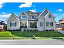 Beautiful two-story home featuring stone and siding, lush lawn, and professional landscaping at 13613 Lake Ridge Ln, McCordsville, IN 46055