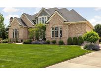 Stunning brick home with a lush green lawn and mature landscaping at 13888 Smokey Ridge Dr, Carmel, IN 46033
