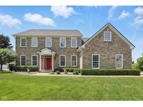 Brick two story home with a manicured lawn and a vibrant red front door exudes classic charm at 16802 Oak Manor Dr, Westfield, IN 46074