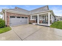 Charming home featuring a brick facade, gray siding, covered front porch, and attached two-car garage at 17309 Graley Pl, Westfield, IN 46074
