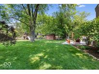 Spacious backyard with a manicured lawn, mature trees, and a patio area for outdoor entertaining at 1408 126Th St, Carmel, IN 46033