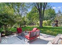 Relaxing backyard patio with comfortable seating, lush landscaping, and a playset at 1408 126Th St, Carmel, IN 46033