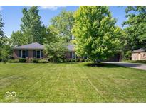 Charming single-story brick home with a beautifully landscaped front yard and mature trees at 1408 126Th St, Carmel, IN 46033