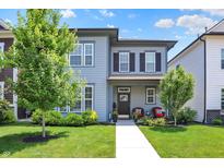Charming two-story home featuring a well-manicured lawn, covered porch with seating and stylish gray siding at 17319 Henslow Dr, Westfield, IN 46074