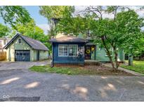 Charming home featuring green siding, blue accents, and a detached garage at 715 Kessler Blvd E Dr, Indianapolis, IN 46220